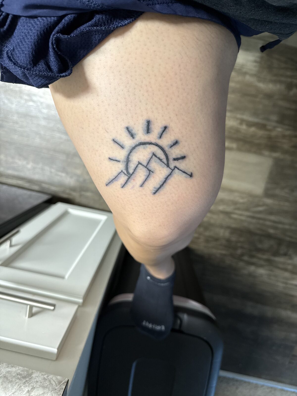 Sun and mountains line tattoo on the leg by Yaa Z Studios